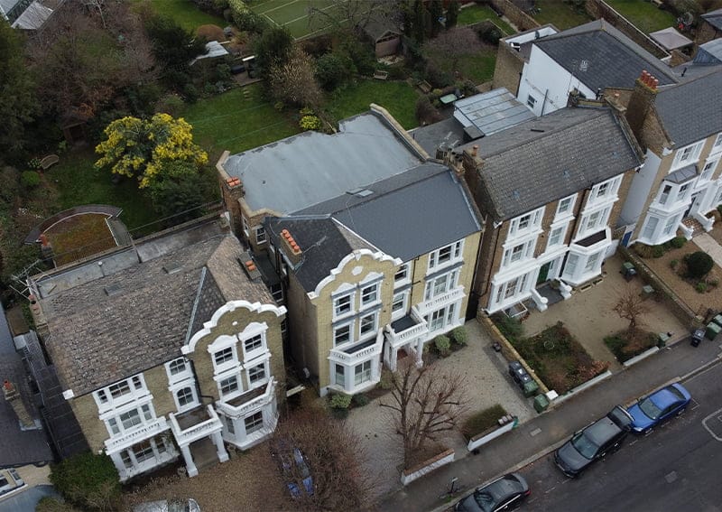 Aerial view of residential houses showcasing architectural features and well-maintained gardens, relevant to discussions on enhancing property value through repointing and home improvements.