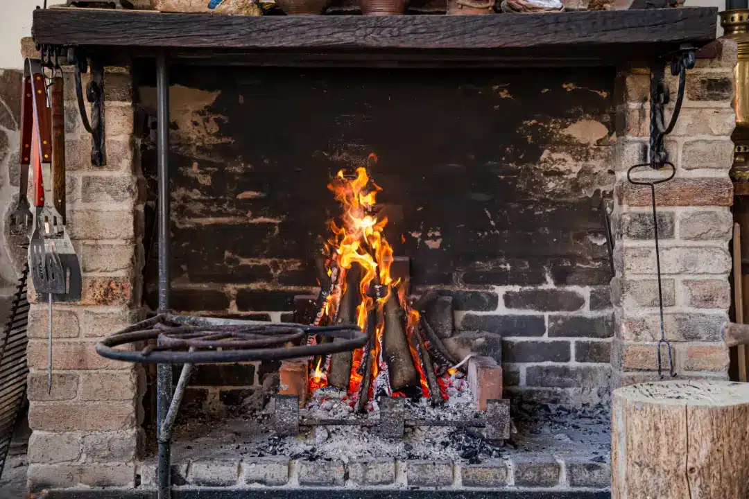 Fireplace with burning logs and visible soot on brick, illustrating the importance of cleaning brick fireplaces for safety and aesthetics.