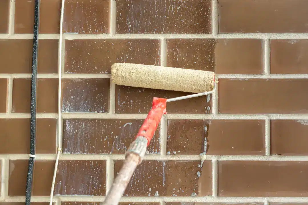 Roller applying cleaning solution to brick wall, showcasing effective brick cleaning techniques for restoration and maintenance.